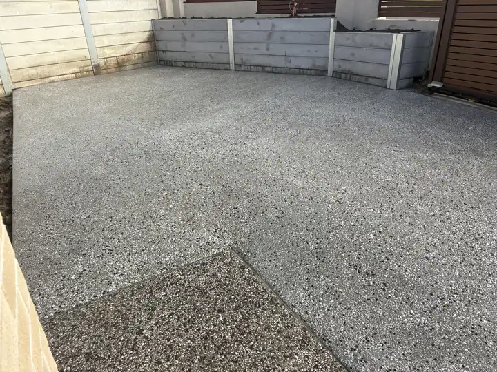 A two tone exposed aggregate driveway bounded by concrete sleeper walls in Springfield Lakes